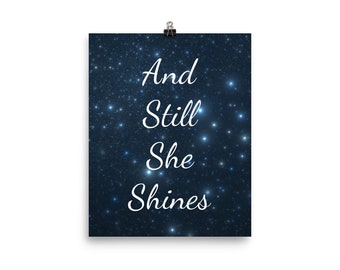 Puede incluir: Un póster azul oscuro con un fondo de cielo estrellado nocturno. El texto "And Still She Shines" está escrito en blanco en cursiva.