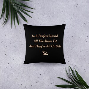 May include: Black throw pillow with the text "In A Perfect World All The Shoes Fit And They're All On Sale" in gold lettering. A gold shoe icon is centered below the text.