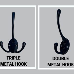 May include: A black metal triple hook with a central vertical prong and two side prongs, and a black metal double hook with one vertical prong and one side prong. Both hooks feature oval mounting plates with two visible screw holes for installation.