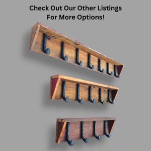 May include: Three wooden wall-mounted coat racks of varying lengths, each featuring a top shelf and multiple black metal hooks. The text "Check Out Our Other Listings For More Options!" is displayed at the top of the image above the racks.