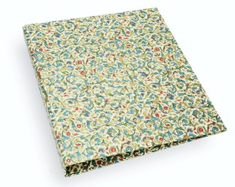 May include: A closed, square-shaped binder with a decorative floral pattern. The cover features a cream-colored background with a repeating design of blue, red, and yellow floral elements. The binder's edges are visible, showing the thickness and construction.
