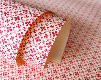 May include: A roll of patterned paper with a repeating floral design in red on a white background. The paper is partially unrolled, revealing the interior of the roll. The pattern is visible on the unrolled portion and the background.