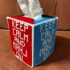 May include: A red and blue tissue box cover with white lettering that reads "Keep Calm and Carry On".