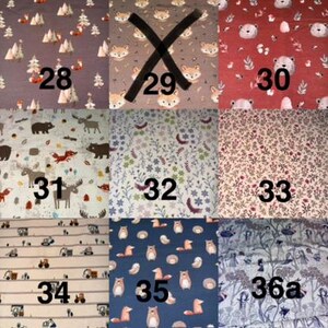 以下が含まれることがあります： 28から36aまで番号が振られた9種類の布地の見本グリッド。森の動物、クマ、キツネ、花柄、建設車両などのパターンが様々な色の背景に描かれています。各セクションには、それぞれ異なる繰り返しグラフィックデザインが表示されています。