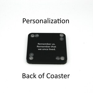 Puede incluir: Posavasos cuadrado negro con esquinas redondeadas y patas de goma transparentes. El posavasos tiene el texto blanco "Remember us. Remember that we once lived." Tambi&eacute;n son visibles las palabras "Personalization" y "Back of Coaster".