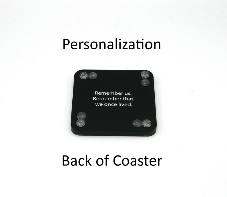 Puede incluir: Posavasos cuadrado negro con esquinas redondeadas y patas de goma transparentes. El posavasos tiene el texto blanco "Remember us. Remember that we once lived." Tambi&eacute;n son visibles las palabras "Personalization" y "Back of Coaster".