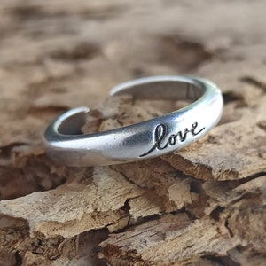 Pu&ograve; includere: Un anello regolabile in argento con la parola "love" incisa sulla fascia.