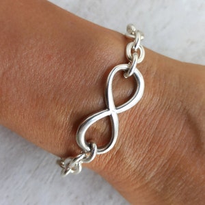 May include: A silver infinity symbol charm bracelet with a chain link design.