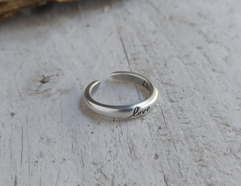 Pu&ograve; includere: Un anello regolabile in argento con la parola "love" incisa sulla fascia.