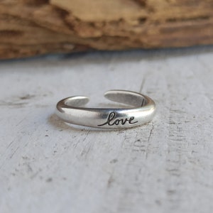 Pu&ograve; includere: Un anello regolabile in argento con la parola "love" incisa sulla fascia.