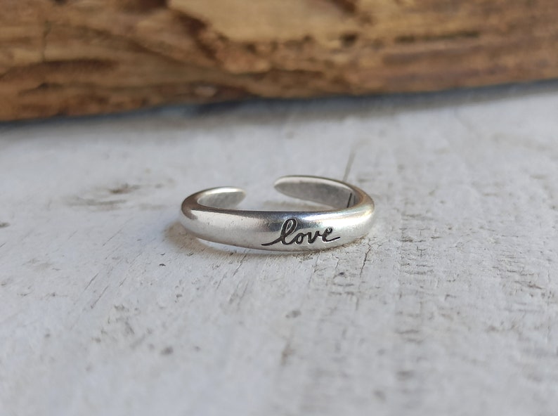 Pu&ograve; includere: Un anello regolabile in argento con la parola "love" incisa sulla fascia.