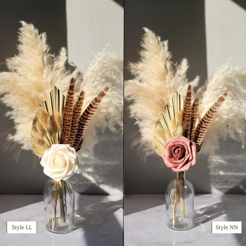 May include: Two glass vases with dried pampas grass, brown feathers, and a single rose. The vase on the left has a white rose, and the vase on the right has a pink rose. The text "Style LL" is in the bottom left corner of the image, and the text "Style NN" is in the bottom right corner of the image.
