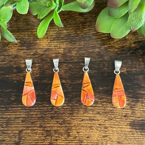 May include: Four teardrop-shaped pendants made of orange and red mosaic stone with silver settings.