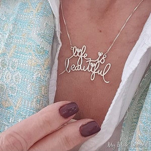 May include: A silver necklace with the words "life is beautiful" in cursive script. The necklace has small clear stones embedded in the letters.