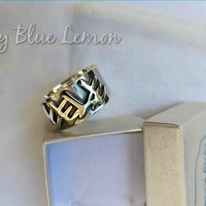 Puede incluir: Un anillo plateado con un diseño calado, apoyado en una pequeña caja. El anillo presenta un patrón repetido. El texto "My Blue Lemon" es visible en el fondo.