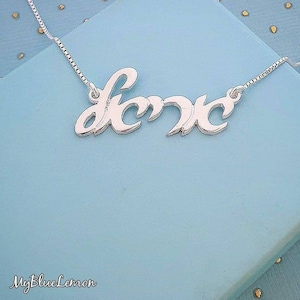 Puede incluir: Un collar de plata con un colgante de nombre en cursiva que dice "Love".