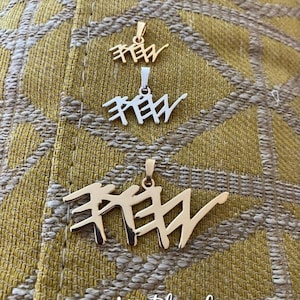 May include: Three pendant necklaces in gold and silver hues, each with a stylized script design. The necklaces are presented against a textured yellow backdrop. The text "My Blue Lemon" is visible at the bottom of the image.