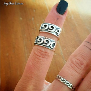 Peut inclure: Deux bagues en argent gravées des années 1990 et 1994. Les bagues sont portées à un doigt.