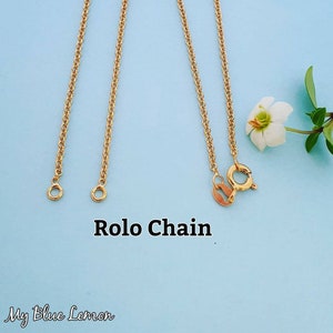 May include: Three gold rolo chains on a light blue background. The chains are different lengths. The text "Rolo Chain" is written below the chains.