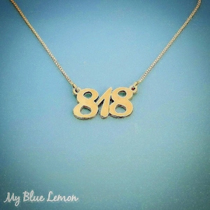 May include: A gold necklace with a pendant featuring the numbers 818.