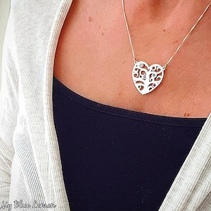 May include: A silver necklace with a heart-shaped pendant featuring a tree design with colorful gemstones. The pendant is intricate and detailed, with a delicate chain.