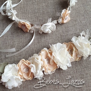 Puede incluir: Dos diademas florales con flores de tela blancas y melocotón. La diadema de arriba es de estilo corona con una cinta blanca. La diadema de abajo es una sola fila de flores.