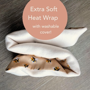 May include: An extra soft heat wrap with a washable cover featuring a repeating pattern of bumblebees on a tan background. The interior lining is a solid cream colour. The text on the image reads: Extra Soft Heat Wrap with washable cover!