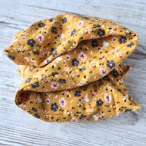 May include: A yellow pillow with a floral pattern. The pillow is made of fabric and has a soft, comfortable texture.