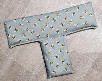 May include: A T-shaped fabric cushion featuring a repeating pattern of small yellow and black bumblebees on a gray background. The item consists of a long horizontal rectangular section attached to a shorter vertical rectangular section.