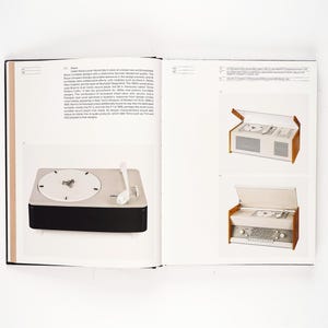 May include: A page from a design book featuring a vintage turntable with a white dial and a black base. A white tone arm rests on the turntable. The book also shows two vintage stereo systems with wooden accents.