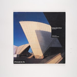 May include: A book cover featuring the Sydney Opera House against a blue sky. The cover has the title "Sydney Opera House" and the author's name, Philip Drew. The publisher's logo, PHAIDON, is at the bottom.