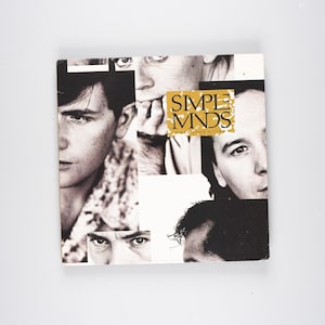Peut inclure: Une pochette d'album en noir et blanc avec un collage d'images du groupe Simple Minds. Le titre de l'album "Once Upon A Time" est imprimé en lettres dorées.