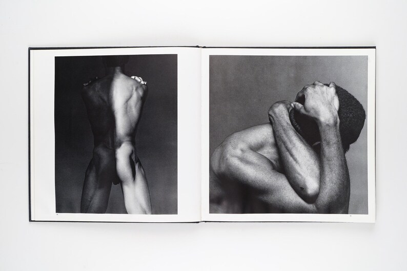 May include: A monochrome photograph in a book, showing two images. One depicts a nude figure's back, the other a person with arms around their head. The images are in black and white.