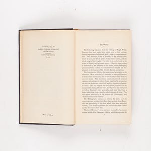 May include: An open book with black covers, lying flat on a white surface. The left page has text from the American Book Company, and the right page has the title "Preface". The book is a vintage edition.