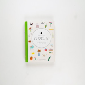 May include: A hardcover book titled "Etiquette" with a green spine and a white cover. The cover features colorful illustrations of various objects and a central circular design with the title. The book is designed to guide individuals on social occasions.