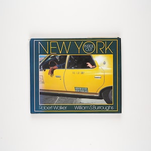 May include: A book cover titled "NEW YORK INSIDE OUT" featuring a yellow taxi cab with passengers. The cover has a dark blue border with gold lettering and the authors' names, Robert Walker and William S. Burroughs, at the bottom.