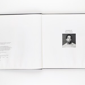 May include: An open book with a black cover. The right-hand page displays a black and white portrait of a man, with the text "In memory of Robert Christian." The left page has text in a small font. The book is open on a white surface.