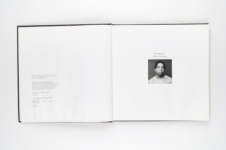 May include: An open book with a black cover. The right-hand page displays a black and white portrait of a man, with the text "In memory of Robert Christian." The left page has text in a small font. The book is open on a white surface.