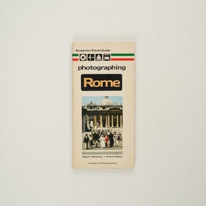 Könnte beinhalten: Ein Amphotor Reiseführer mit dem Titel "fotografieren Rom" mit einem Foto des Petersdoms auf dem Cover.