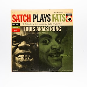 May include: A square vinyl record cover titled Satch Plays Fats, A Tribute to the Immortal Fats Waller by Louis Armstrong and his All-Stars. The cover features a split-tone green and black photographic portrait of two faces with bold red and black text.