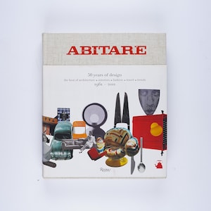 May include: A book titled "Abitare: 20 years of design" with a white cover and a collage of colorful images of furniture, objects, and a car. The text "the best of architecture, interiors, a fashion, a travel, a trends 1981-2001" is printed on the cover.