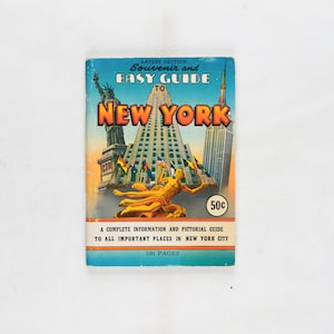 May include: A vintage travel guide titled "Souvenir and Easy Guide to New York." The cover shows illustrations of the Statue of Liberty, the Empire State Building, and other New York landmarks. The guide is 100 pages long and priced at 50c.