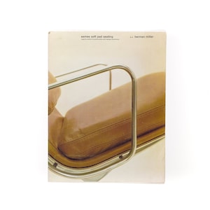 Op de afbeelding: Een close-up van een bruine leren stoel met een chroom frame. De stoel maakt deel uit van de Herman Miller "Eames Soft Pad Seating" collectie.