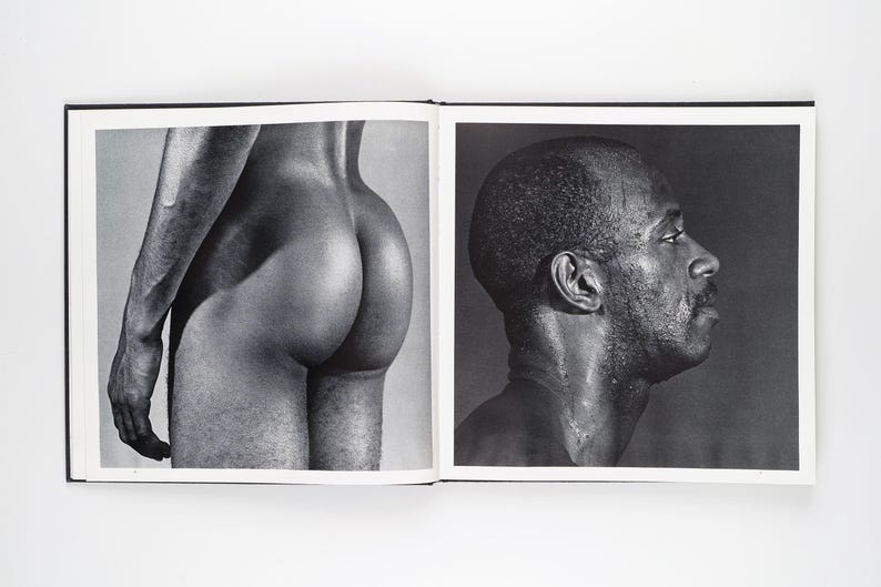 May include: A monochrome photograph of an open book. One page shows a person's rear, the other a profile of a person's face and neck. The images are in black and white.