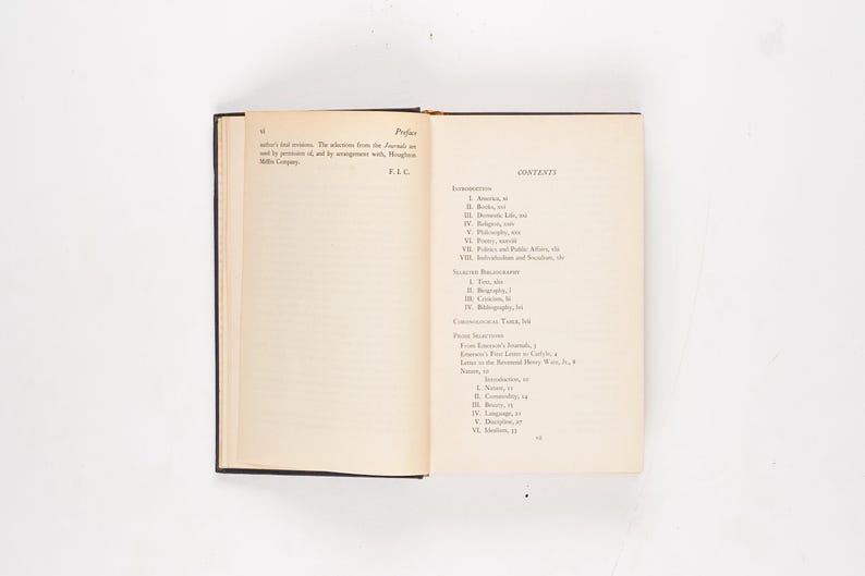 May include: An open book with a black cover, displaying the preface and table of contents. The pages are off-white with black text. The book is on a white surface.