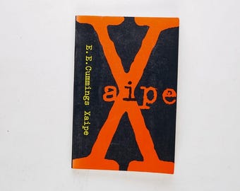 May include: A book cover with a large orange "X" on a black background. The text "aipe" is in yellow letters on the "X". The author's name, "E. E. Cummings", is printed vertically on the left side of the cover in yellow letters.