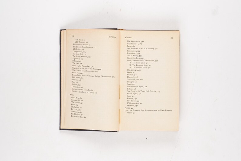 May include: An open book with a black cover, displaying two cream-colored pages filled with text. The left page lists chapter titles, while the right page shows a table of contents. The book is set against a white background.