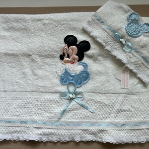 Puede incluir: Juego de toallas blancas para beb&eacute; con aplique de Mickey Mouse. El juego incluye una toalla grande con un dise&ntilde;o de Mickey Mouse y una toalla m&aacute;s peque&ntilde;a con una cabeza de Mickey Mouse. Ambas toallas tienen cinta azul y ribete de encaje.