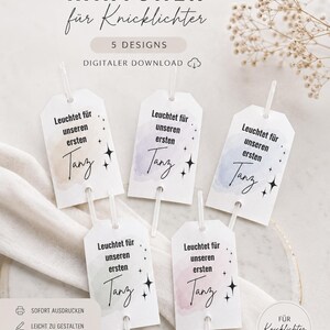 Pode incluir: Uma coleção de cinco etiquetas brancas com o texto "Leuchtet für unseren ersten Tanz" em escrita preta, cada uma com um fundo de aquarela diferente. As etiquetas estão presas a palitos de plástico transparente. A parte superior da imagem tem o texto "KÄRTCHEN für Knicklichter".