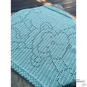 May include: A light blue crocheted baby blanket with a decorative pattern of hearts. The blanket has a braided border.